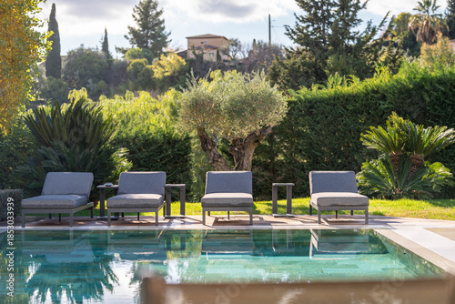 Luxury villa swimming pool with sun loungers and Mediterranean garden landscape