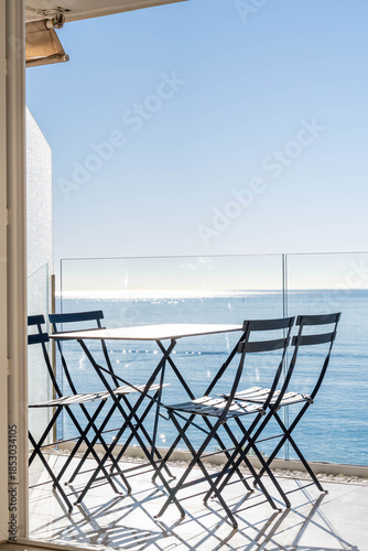 Minimalist seaside balcony with folding chairs overlooking calm blue ocean