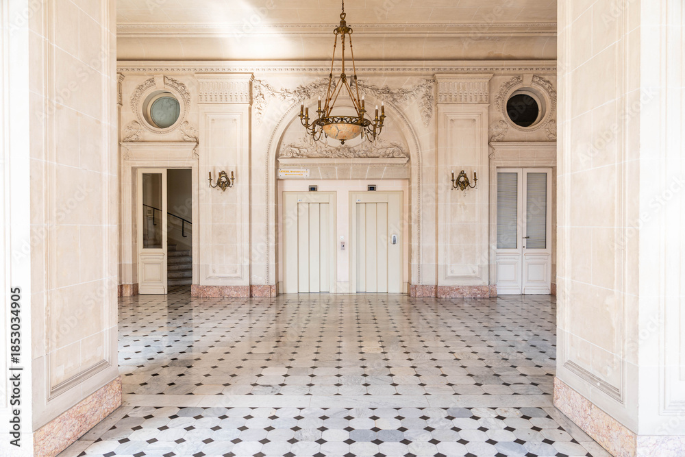 Fototapeta premium Elegant historic interior hall with marble columns, patterned floor and chandelier in classical palace