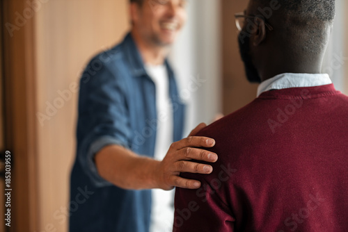 Tableau sur toile Friendly Encounter: Man Reaches to Comfort Friend in Warm Indoor Doorway Moment