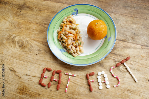 eat fast concept made with pills and clock on wooden background