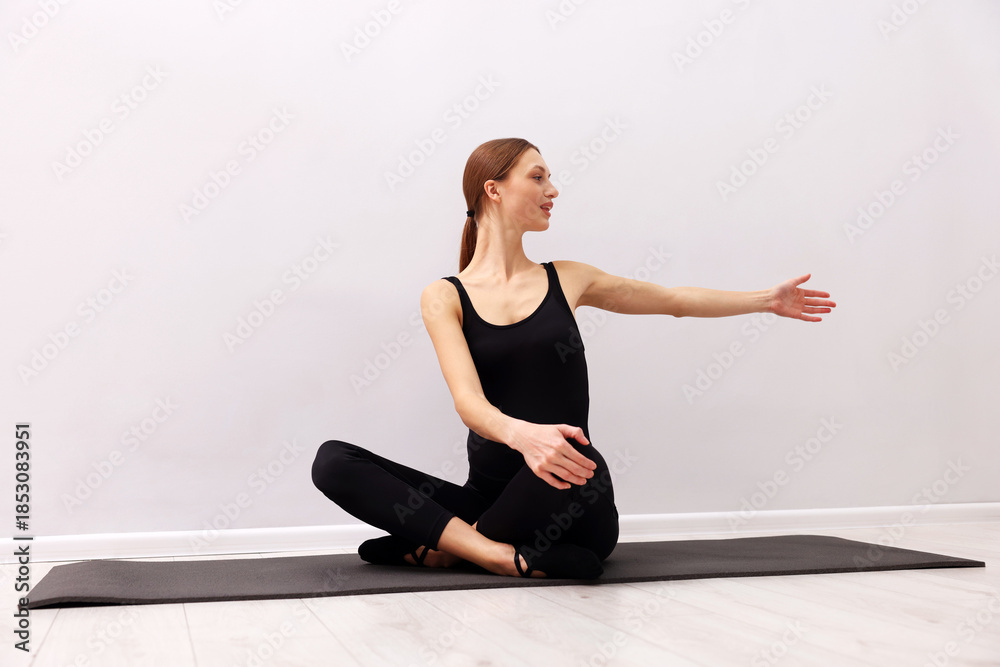 Fototapeta premium Pregnant woman practicing yoga on mat indoors