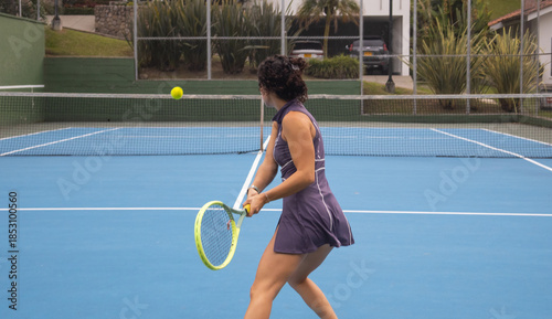 Action shot of a young female tennis player executing a two-handed backhand swing during a practice session. Concept of technical learning, resilience, and effort in healthy sports hobbies.