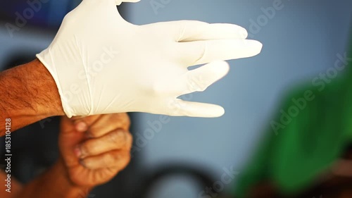Close-up video of a man wearing rubber medical gloves, representing healthcare hygiene, safety measures, and professional medical preparation.