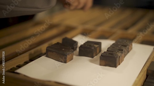 
An old-fashioned printing press operator places the iron letters for printing an old newspaper.