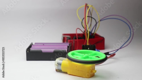 BO motor or also known as hobby motor with its shaft connected to wheel controlled by micro controller and battery on the background