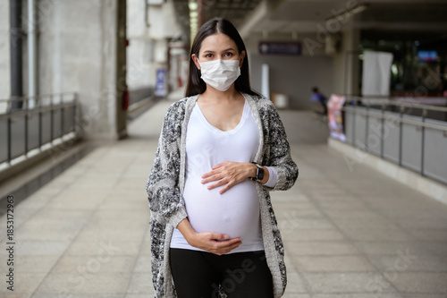 Pregnant woman wearing protective mask outdoors, health and maternity concept.