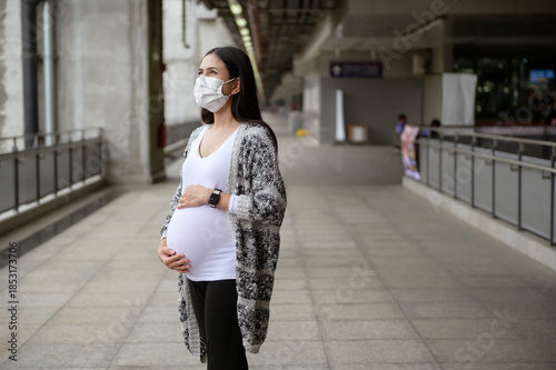 Pregnant woman wearing protective mask outdoors, health and maternity concept.