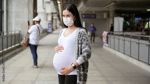 Pregnant woman wearing protective mask outdoors, health and maternity concept.