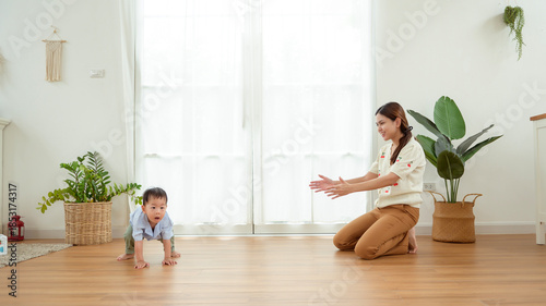 Boy Takes His First Steps at Home While Holding His Mother's Hand in a Warm Living Room Setting