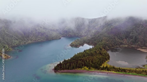 Volcanic lake in foggy conditions inside mountain caldera. Atmospheric nature scene from Azores islands, drone footage