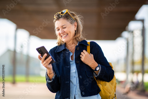 Mature woman smiling while checking smartphone outdoors