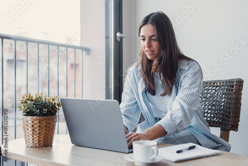 Successful virtual teamwork. Laughing gen z girl remote employee blended learning student communicate by videocall via notebook sit at table in cozy coworking space collaborate on online group project