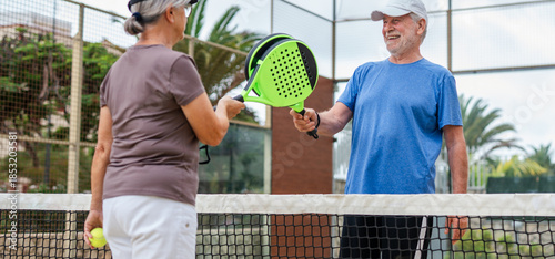 Canvastavla Senior couple playing paddle tennis or padel, outdoors in padel court enjoying and having fun together