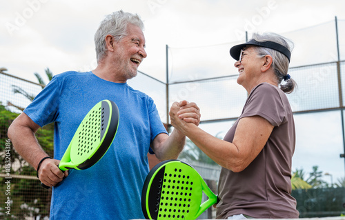 Cuadro en lienzo Senior couple playing paddle tennis or padel, outdoors in padel court enjoying and having fun together