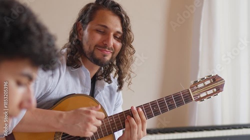 LGBTQ music teacher playing acoustic guitar during a lesson indoors