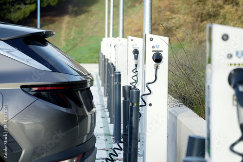 Parte trasera de un coche eléctrico enchufado a puntos de carga urbanos para cargar la batería, movilidad sostenible cero emisiones