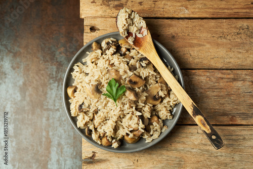 Cooking Rice with Mushrooms on a wooden table with a spoon and herbs