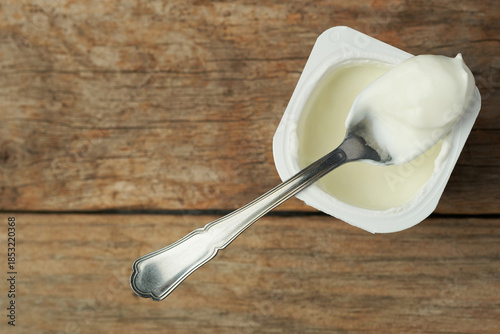 Yogurt in a Container on a Wooden Table With a Spoon