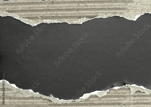 Rough torn cardboard paper background with ripped edges and dark copy space.