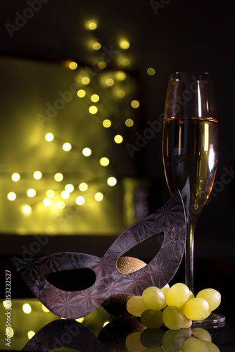 Bunch of grapes next to champagne glass and mask for New Year's Eve