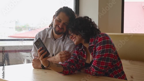 Happy LGBTQ friends looking at smartphone screen after taking selfie at cafe