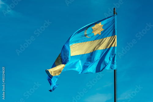 A waving Szekler flag against the blue sky. Harghita country, Romania.