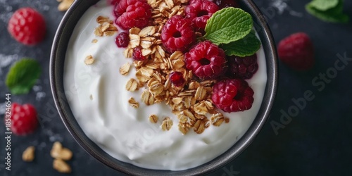 Healthy and appetizing breakfast option with fresh raspberries, crunchy granola, and creamy yogurt in a bowl.