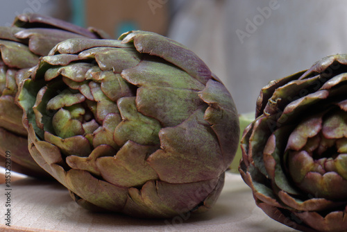 Fresh Purple Artichokes on Cutting Board with Mediterranean Ingredients: Olive Oil, Lemon, and Garlic