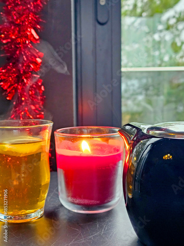 Christmas still life with burning candles on the windowsill and Christmas decorations. Tea