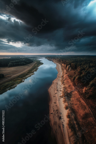River winding through forest under dramatic storm clouds