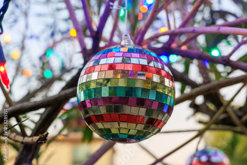 Colorful Rainbow-mirrored Disco Ball Ornament Hanging in between Tree Twigs, Shallow DOF