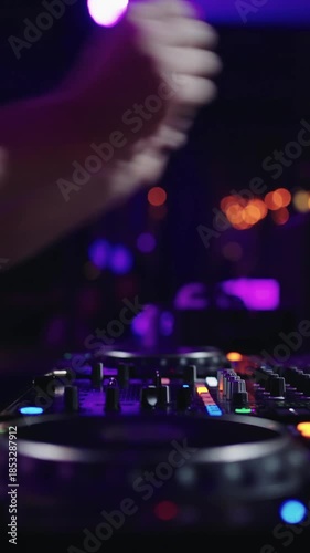 Close-up of DJ hands mixing electronic music on professional controller with colorful lights in a dark nightclub party atmosphere during live set