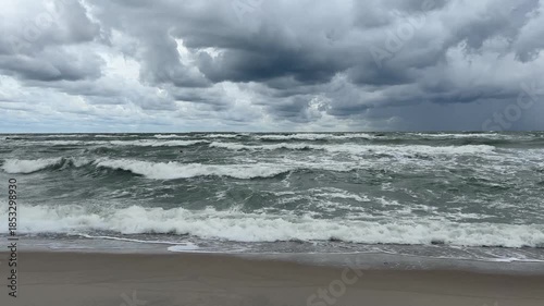 Baltic sea ocean foamy storm waves surf hitting gray empty shore dramatic sky strong wind wild seascape beach coastline spray