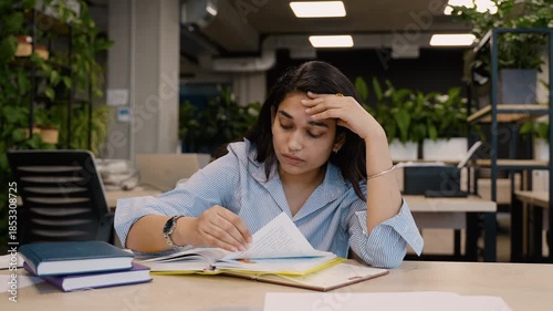 Stressed Indian student experiencing headache while studying for exams