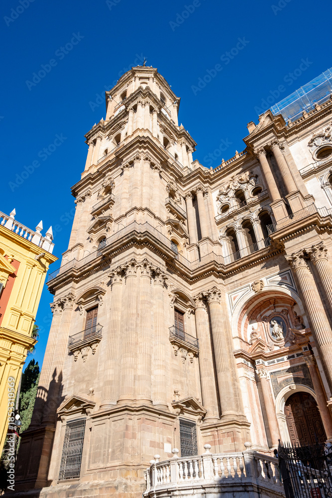 Fototapeta premium The Malaga cathedral stands tall in bright daylight against the sky.