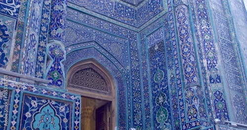 Richly decorated facade of historic Islamic architecture in Samarkand featuring detailed ceramic tiles, geometric ornament, and traditional arched doorway.