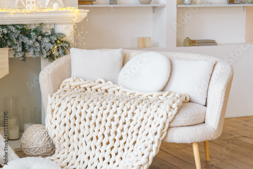 Photos Neutral white boucle sofa with chunky knitted blanket with soft pillows in a cozy festive living room
