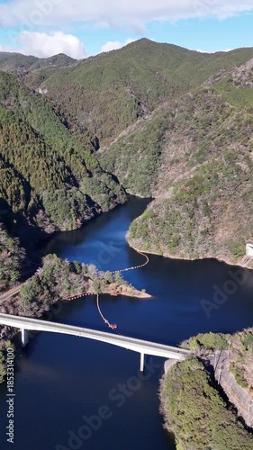 日本のドローン映像　冬の晴れた日にダム湖の橋に近づきながら空撮