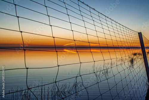 Sunset behind wire fence at Doñana National Park wetlands