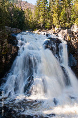 Chute du Diable waterfall in Mont-Tremblant National Park, Quebec, Canada. Long exposure view of powerful flowing water surrounded by forest and rocks.
