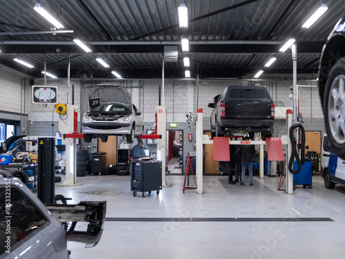 Professional automotive service center interior with vehicles on lifts technicians and organized equipment layout