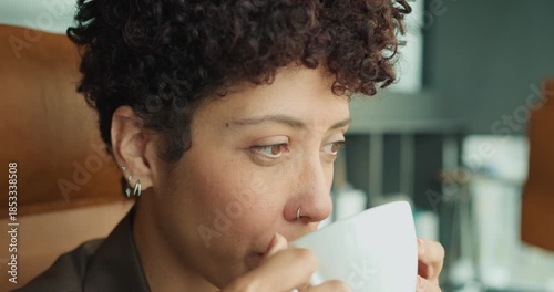 Introspective individual gazing through window while enjoying coffee