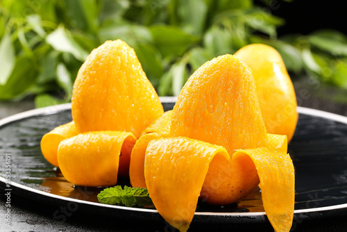 Fresh Peeled Mangoes with Water Droplets on Black Plate
