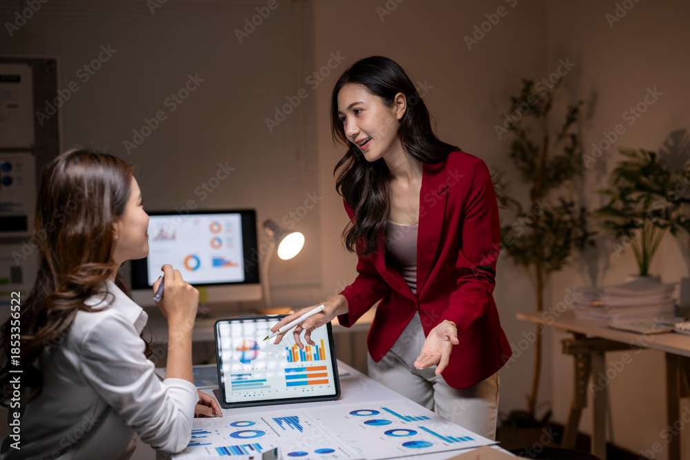 Fototapeta premium Businesswomen analyzing data charts in a late night meeting