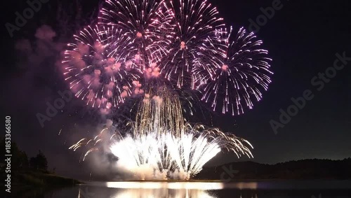 Vibrant Long Exposure of Explosive Fireworks Bursting Over Serene Lake in Night Sky
