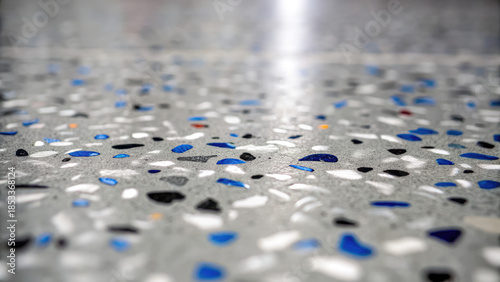 Gray epoxy coating with blue black white chips concept. Close-up view of decorative terrazzo flooring with colorful chips.