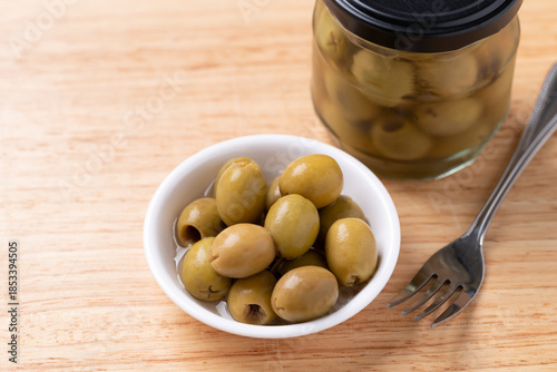 Pickled olives, Pitted green olives in a bowl and glass jar on wooden background