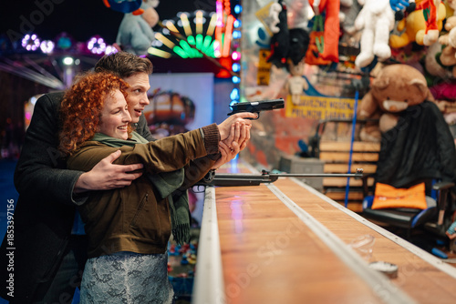 Young couple enjoying shooting gallery game at amusement park