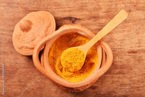Dry curry powder in bowl on wooden table